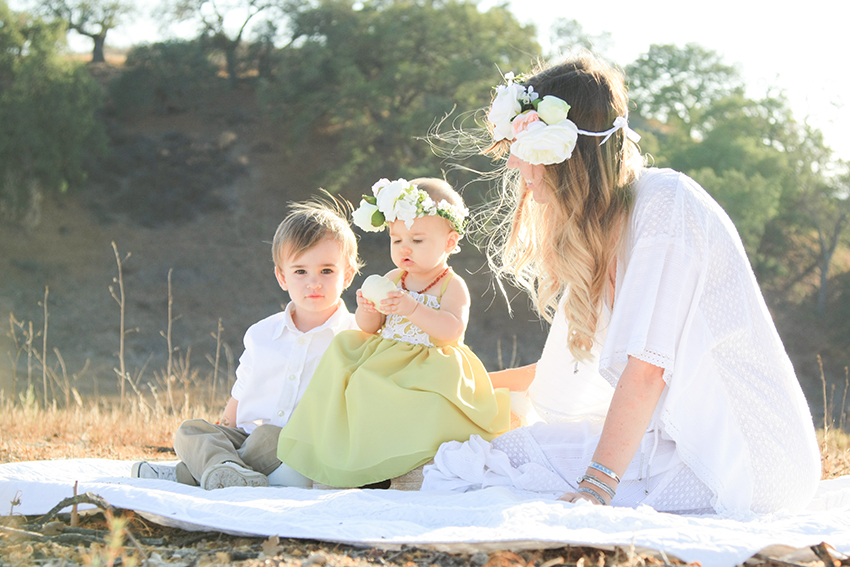 mother and toddler boy with baby girl in a sunlit open field. life lately: an update