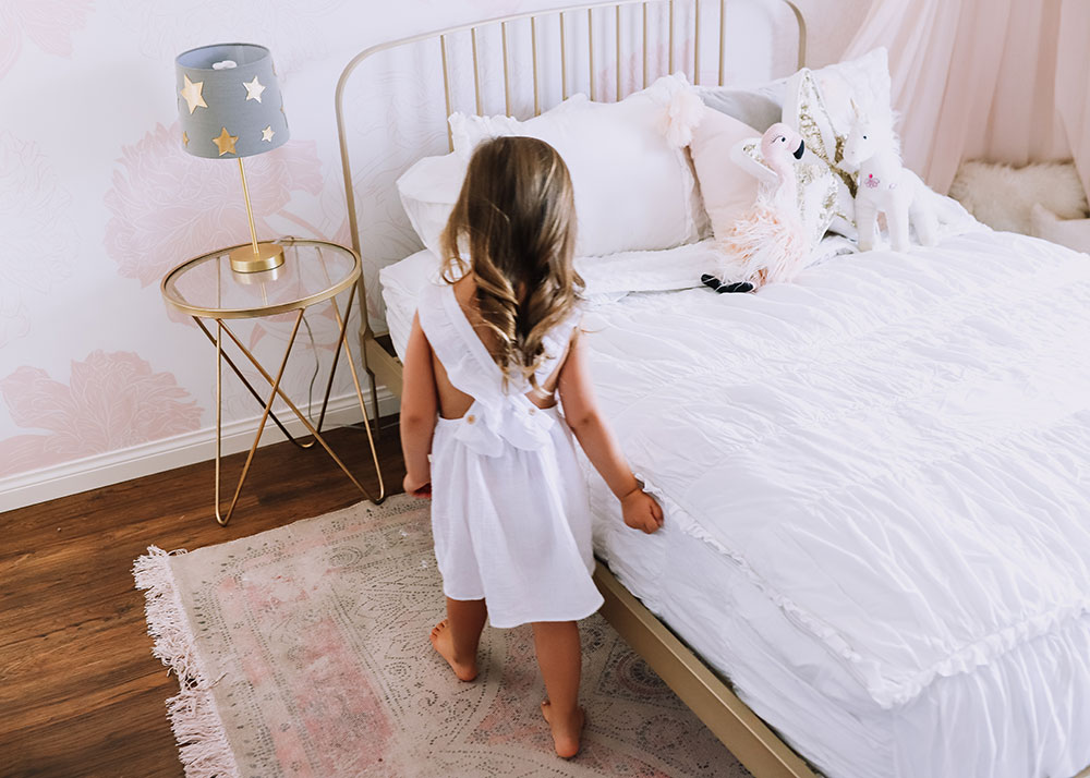 little girl making her bed to help with keeping the house clean | thelovedesignedlife.com #totalhomeprotection #zevo #girl's room