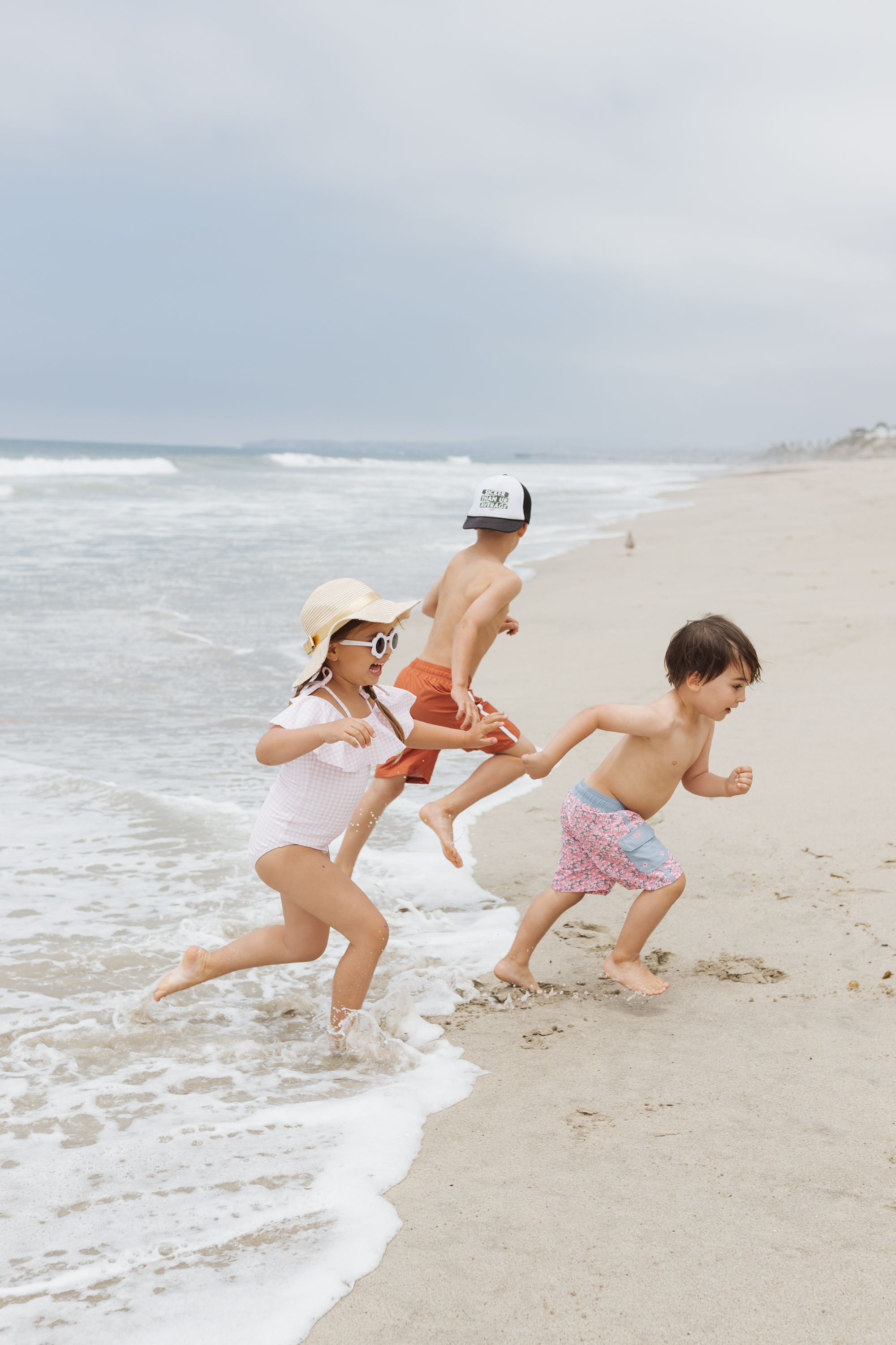 three kids running in the waves on the beach