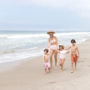 mom and three kids walking on the beach in swimsuits