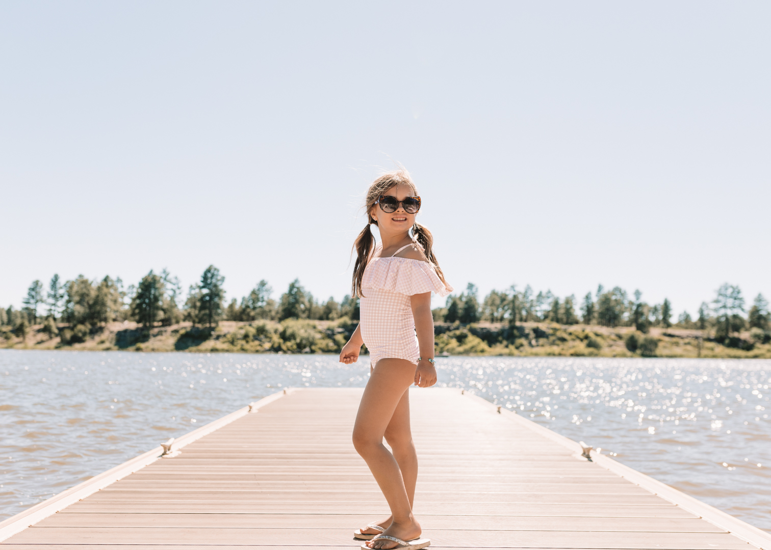 little girl in a swimsuit on a dock to the lake