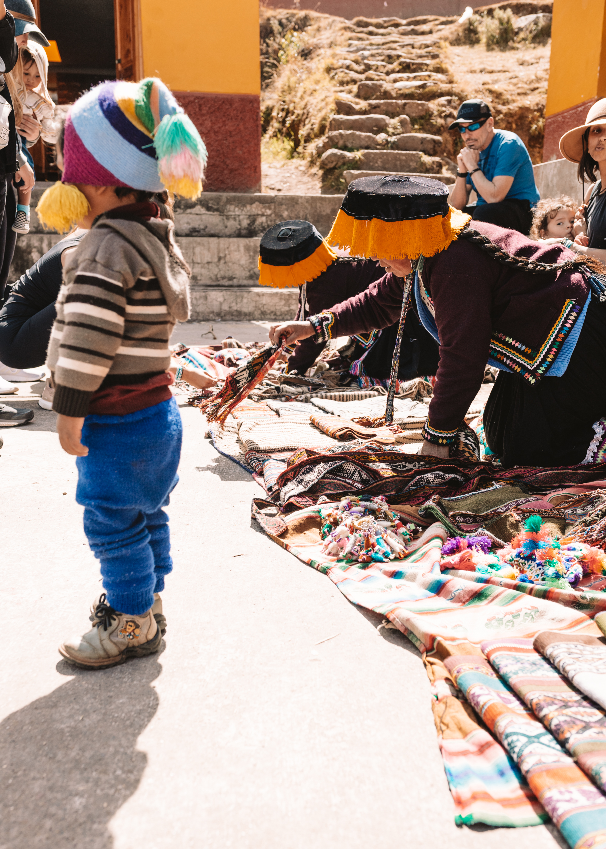 women laying out their wares to sell, while a sweet little toddler boy looks on. #peru #magicaljourney #travel