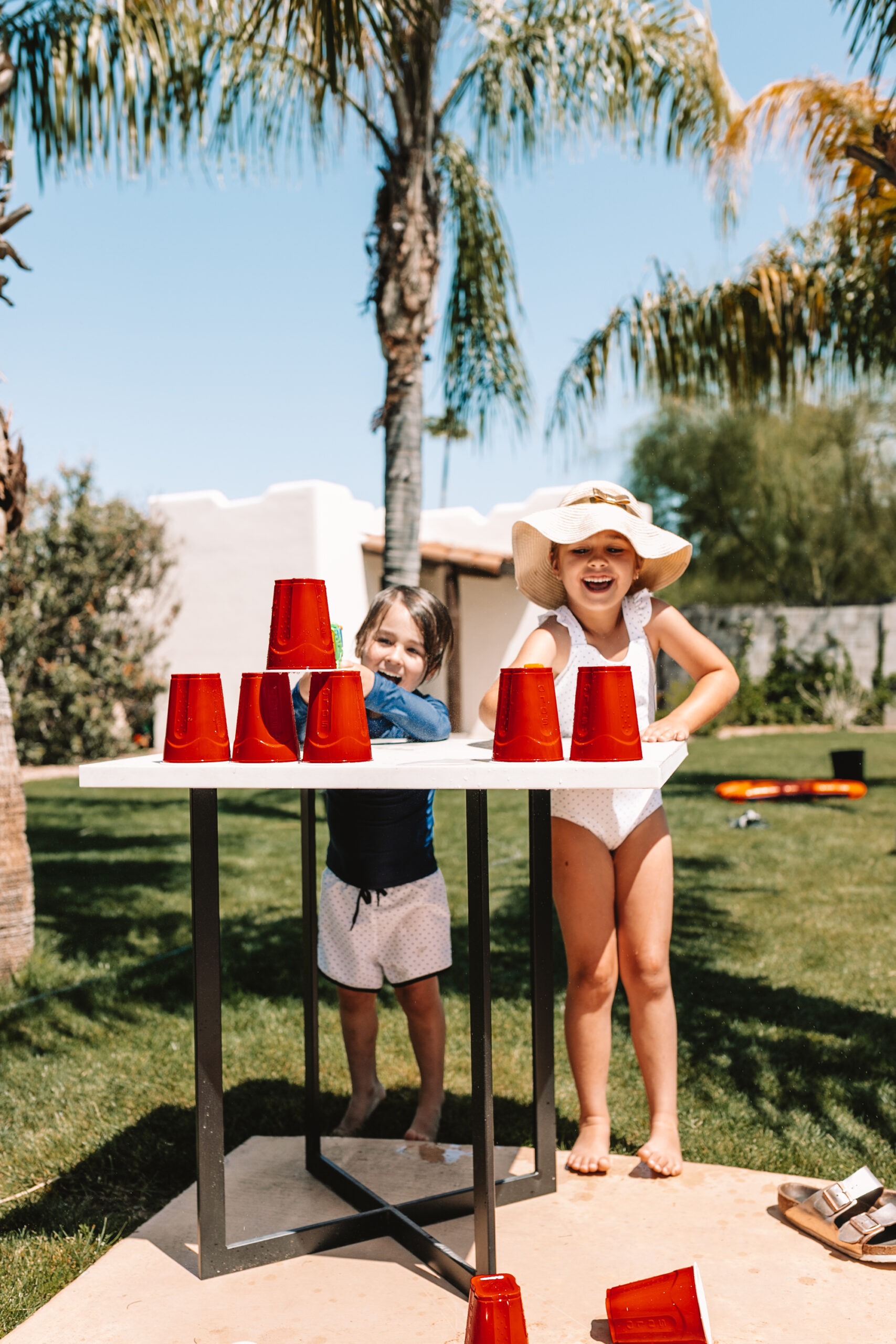 see who can knock over all of the cups off the table with the water gun first! (pushing off the table only when the water gun isn't working lol) #thelovedesignedlife #backyardfun #fielddayactivity #waterplay 