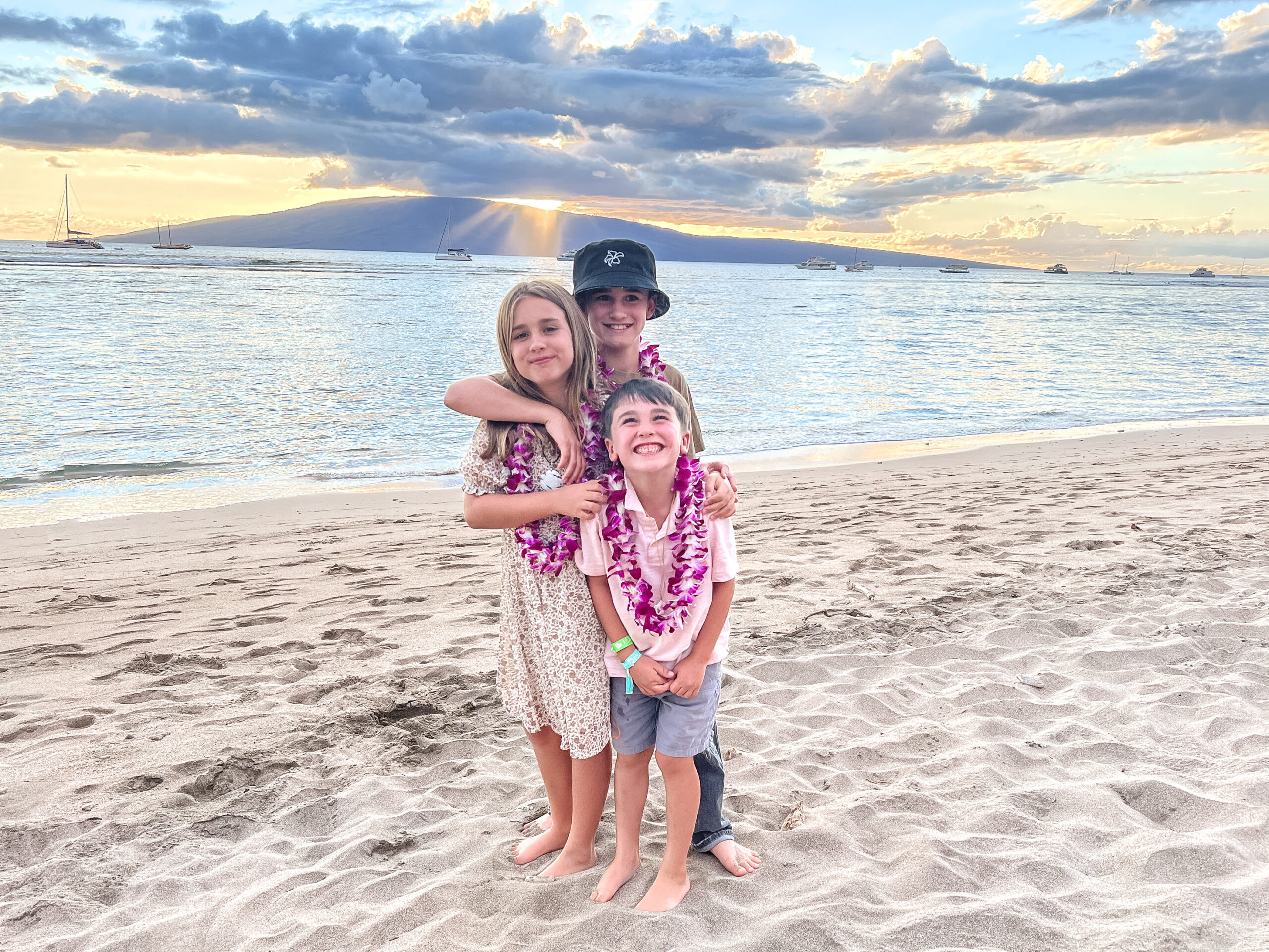 the three kiddos enjoying the sunset at the feast of lele #luau #visithawaii #thedldtravels